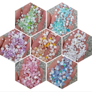 May include: Assortment of six colors of small flower-shaped sprinkles. The colors are light green, lavender, yellow, white, pink, and light blue.