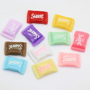 May include: Assortment of ten colorful candy wrappers with the word "Sweet" printed on each. The wrappers are in various colors, including red, yellow, purple, green, brown, white, pink, and blue.