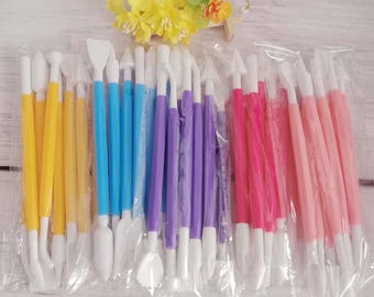 May include: A set of 20 plastic cake decorating tools in various colors, including yellow, blue, purple, pink, and red. The tools have different shapes and sizes for creating various designs on cakes.