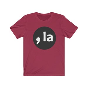 May include: A maroon t-shirt with a black circle and white text that says ",la"