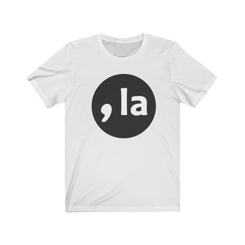 May include: White t-shirt with a black circle containing a white comma and the word "la" in white.