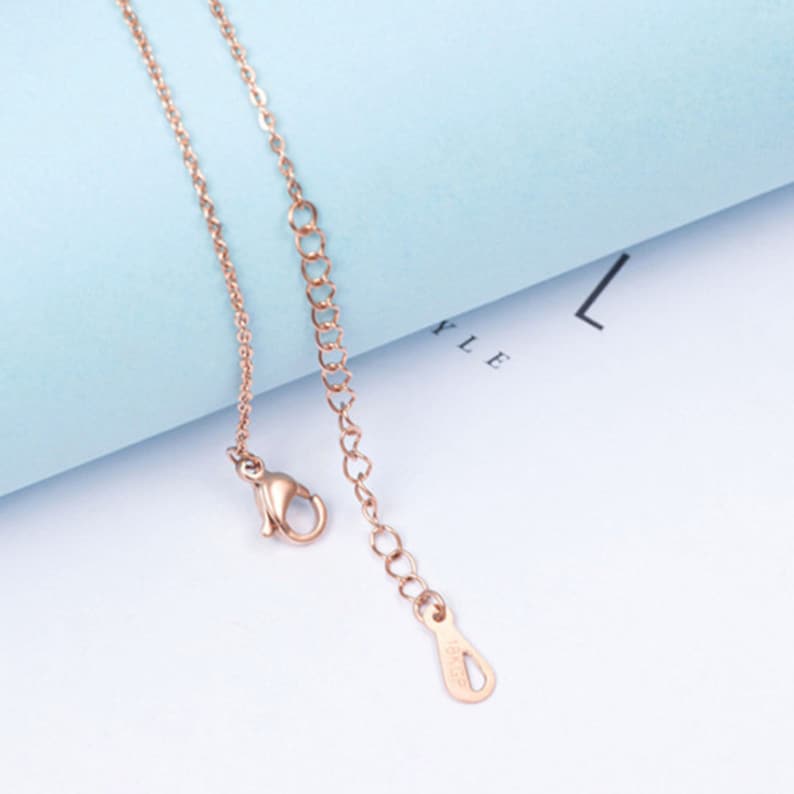 Puede incluir: Un collar de cadena de oro rosa con un cierre de langosta y una peque&ntilde;a etiqueta con la palabra "925" en ella.