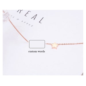 Puede incluir: Un delicado collar de color dorado con un peque&ntilde;o dije en forma de estrella. La cadena es fina y presenta un dise&ntilde;o delicado de eslabones. El collar se muestra sobre una superficie blanca con las palabras "REAL & STYLE" visibles en el fondo.
