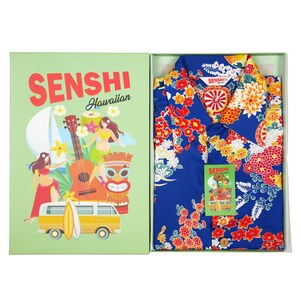 May include: A blue Hawaiian shirt with a floral print and the text "Senshi Hawaiian" on the box. The shirt is in a gift box with a green background and a cartoon illustration of a ukulele, a surfboard, and a tiki.