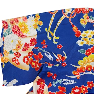 May include: A blue fabric with a floral pattern. The flowers are red, yellow, and white. The fabric has a shiny finish.