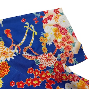 May include: Blue fabric with a floral pattern in shades of red, orange, yellow, and white. The flowers are arranged in a repeating pattern and are surrounded by green leaves.
