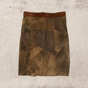 May include: A brown leather skirt made of patchwork pieces. The skirt has a brown leather waistband.
