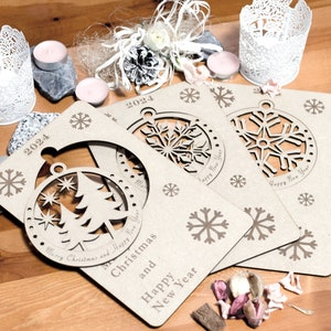 May include: Three brown cardboard Christmas ornaments with cut-out snowflake designs. The ornaments are decorated with the text "Merry Christmas and Happy New Year" and "2024".