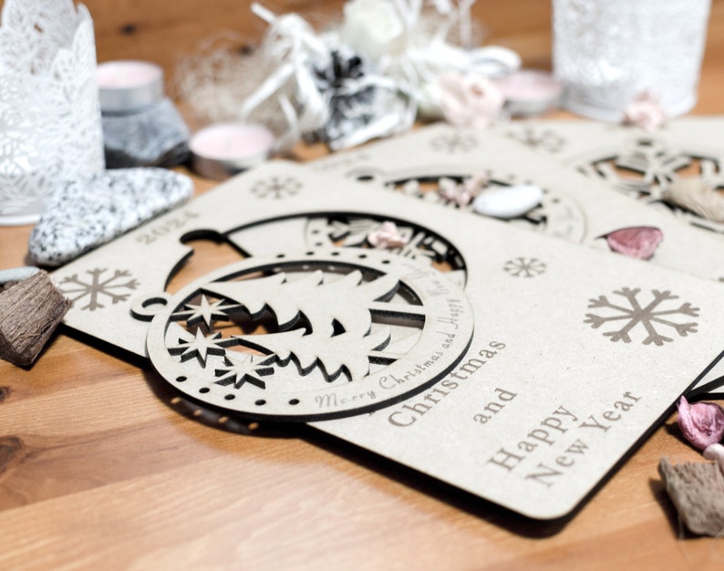 May include: Three wooden Christmas ornaments with a snowflake design and the text "Merry Christmas and Happy New Year".