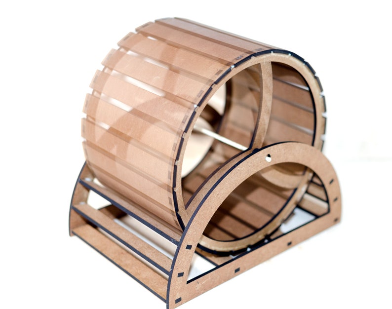 May include: A cylindrical exercise wheel for small animals constructed from light brown wood and clear acrylic panels. The structure features a circular frame with horizontal slats and a sturdy base, designed with visible interlocking joints and edges.