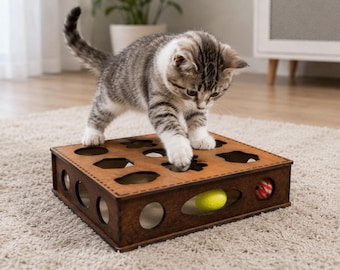 Puede incluir: Una caja de rompecabezas de madera marrón para mascotas con varios recortes geométricos en la superficie superior y aberturas ovaladas en los lados. Un pequeño gatito atigrado gris y blanco está sobre la caja, alcanzando un recorte con una pata.