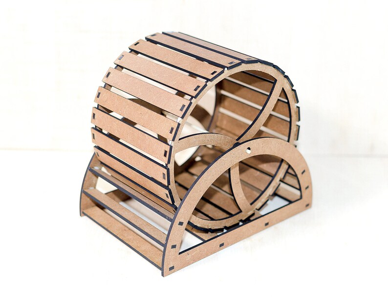 May include: A light brown wooden exercise wheel for small animals, featuring a cylindrical drum constructed from horizontal slats with dark edges, supported by a semi-circular base frame with a central circular support structure.