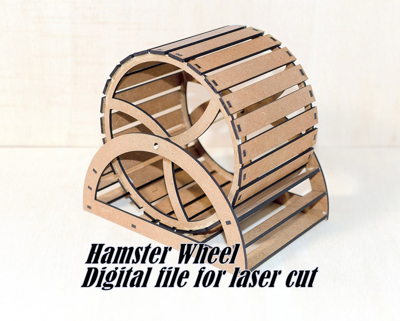 May include: A light brown wooden hamster wheel with dark edges, featuring a cylindrical drum and a curved support stand. The text Hamster Wheel Digital file for laser cut is printed in black at the bottom of the object.