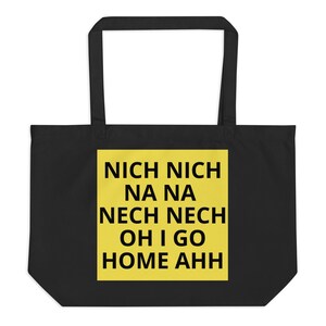 Puede incluir: Bolso tote negro con un cuadrado amarillo que muestra el texto "NICH NICH NA NA NECH NECH OH I GO HOME AHH" en negrita. El bolso tiene dos asas negras y probablemente está hecho de tela.