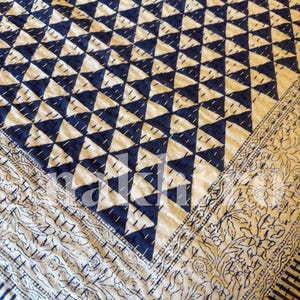 May include: A white and blue kantha quilt with a geometric pattern of triangles. The quilt has a border with a floral design.