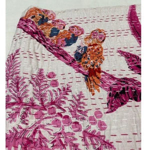 Puede incluir: Una colcha kantha blanca con un dise&ntilde;o de b&uacute;ho rosa y naranja. La colcha est&aacute; cosida a mano con una puntada corrida y presenta un patr&oacute;n floral.