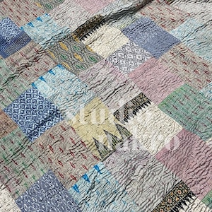 May include: A patchwork quilt made of various fabrics in shades of blue, green, pink, and beige. The quilt is made of squares of different sizes and patterns, and the seams are visible.