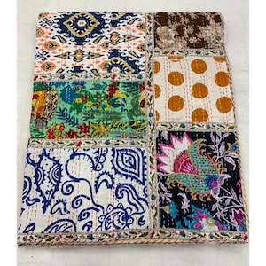 Op de afbeelding: Een patchworkdeken met een verscheidenheid aan kleurrijke bloemen- en geometrische patronen. De deken is gemaakt van verschillende stoffen die in een rasterpatroon aan elkaar zijn genaaid. De deken is een levendig en kleurrijk stuk woondecoratie.