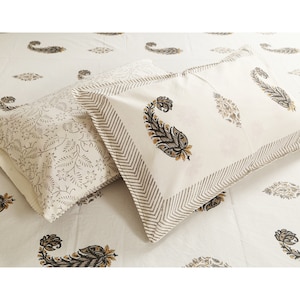 May include: Two white cotton pillowcases with a paisley pattern in shades of brown and yellow. The pillowcases have a border of brown stripes.