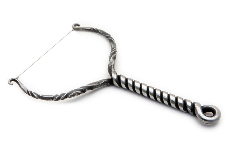 May include: A silver metal cheese cutter with a twisted handle and a wire loop. The handle is twisted and has a loop at the end.