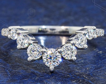 May include: A silver-toned V-shaped band ring featuring seven round-cut clear stones set in a prong setting. The stones are arranged in a graduated pattern, with the largest stone centered at the point of the V, tapering to smaller stones on each side.