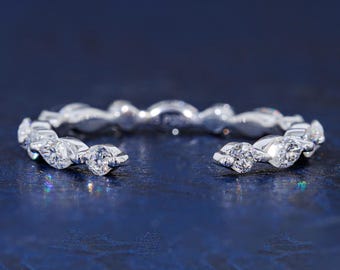 May include: A silver-toned open ring featuring a series of alternating round and marquise-cut clear stones set along the band. The ring has a gap at the front, showcasing a delicate design with multiple faceted gems that catch the light.