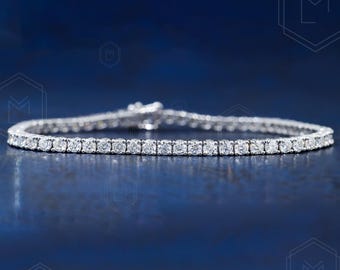 May include: A silver tennis bracelet with a row of small, round diamonds.