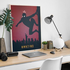 Op de afbeelding: Een rode en zwarte poster met een silhouet van een superheld in een Spider-Man-pose, met de tekst "AMAZING" onderaan.