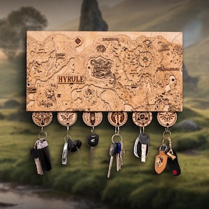 Op de afbeelding: Houten sleutelhouder met een gedetailleerde kaart van Hyrule en sleutelhangers eronder. De sleutelhangers hebben cirkelvormige ontwerpen met symbolen. Het woord "HYRULE" staat op de kaart.