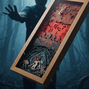 May include: A wooden framed clock with a layered design depicting a scene with figures on bicycles, a monster, and a forest. The clock face has red numerals and hands. The frame is light brown.
