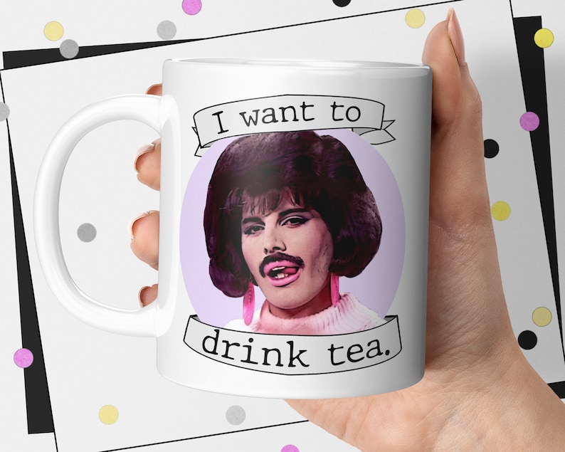 May include: White ceramic mug with a purple background and a cartoon image of Freddie Mercury with the text "I want to drink tea."