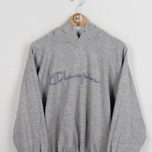 May include: A gray Champion hoodie with a blue embroidered logo. The hoodie has a drawstring hood and a kangaroo pocket.