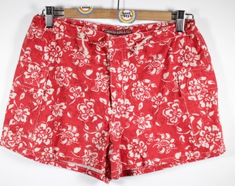 May include: Red floral print shorts with a white background. The shorts have a drawstring waist and two pockets. The label reads "Carmens Jeans & Co."