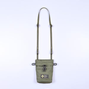 May include: A green canvas pouch with a drawstring closure and an adjustable shoulder strap. The pouch has a small logo patch with the text "Sakura" on it.