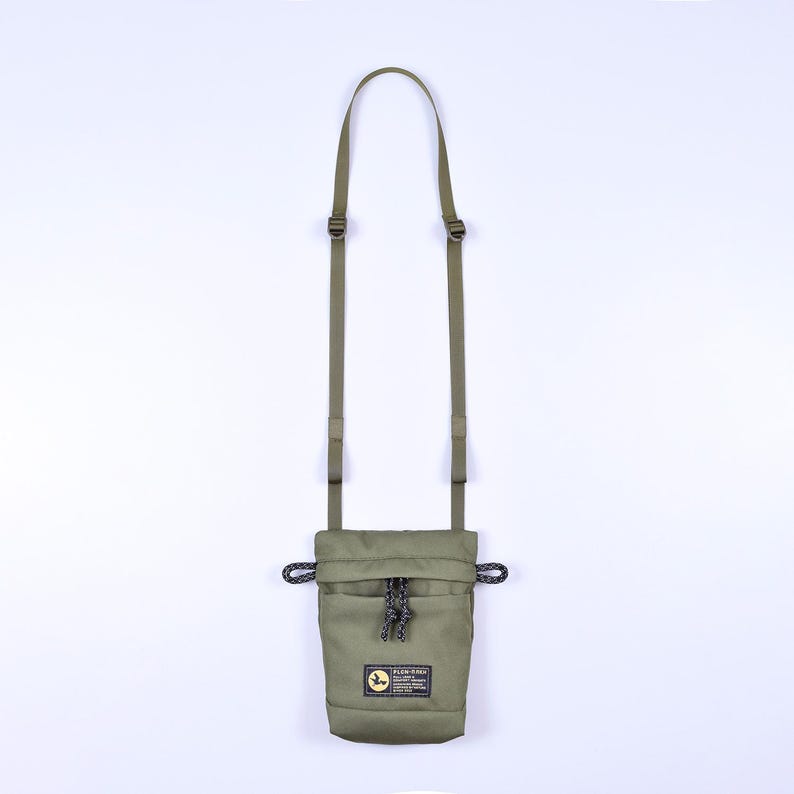 May include: A green canvas pouch with a drawstring closure and an adjustable shoulder strap. The pouch has a small logo patch with the text "Sakura" on it.