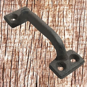 Könnte beinhalten: Ein dunkelgrauer Gusseisen-Griff mit gebogenem Bügel und rechteckigen Montageplatten. Jede Platte hat ein Loch zur Montage. Der Griff ist für eine rustikale oder industrielle Ästhetik konzipiert.