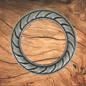 May include: A silver-toned metal ring with a decorative, braided design. The ring is circular and has a smooth, polished finish.