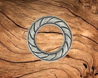 Könnte beinhalten: Silberfarbener Metallring mit einem dekorativen Wirbelmuster. Der Ring ist rund und hat eine glatte, polierte Oberfläche.
