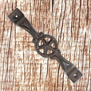 Può includere: Una maniglia per porta rustica in ghisa con un design a stella. La maniglia è di colore marrone scuro e ha una finitura anticata.