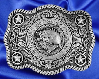 May include: Silver-toned belt buckle with a detailed design featuring a bass fish jumping out of the water, surrounded by ornate scrollwork and four five-pointed stars.