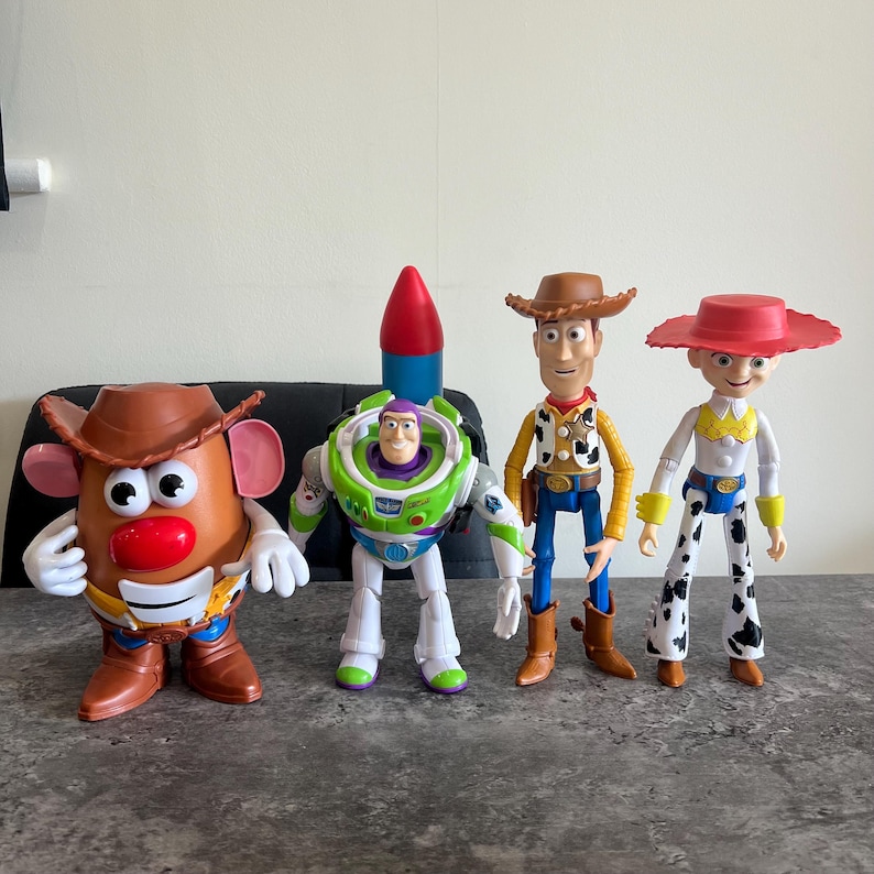 May include: Four Toy Story character figures: Mr. Potato Head, Buzz Lightyear, Woody, and Jessie. Mr. Potato Head wears a brown cowboy hat. Buzz Lightyear has a rocket on his back. Woody and Jessie wear cowboy hats and boots.