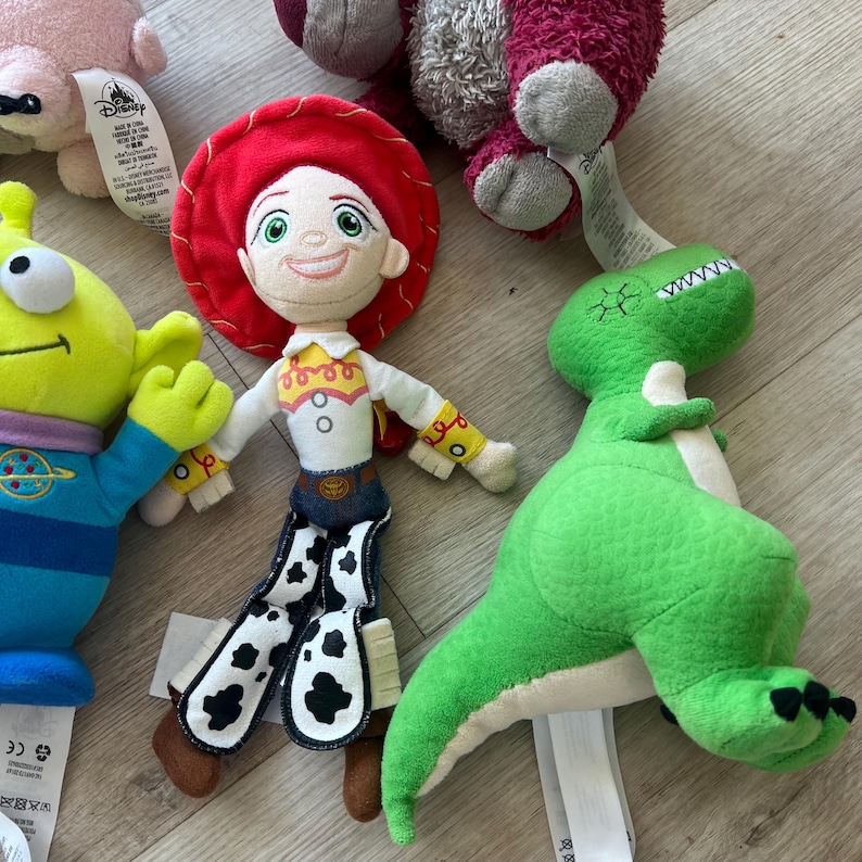 K&ouml;nnte beinhalten: Eine Sammlung von Pl&uuml;schtieren mit Charakteren aus dem Toy Story-Franchise. Die Spielzeuge umfassen Jessie, einen gr&uuml;nen Dinosaurier und einen dreiaugigen Au&szlig;erirdischen. Die Spielzeuge sind aus weichen Materialien gefertigt und haben detaillierte Gesichtsz&uuml;ge.