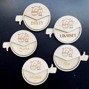 May include: Five wooden round dishwashing signs with a thumbs up or thumbs down icon. The signs have the words "Dirty", "LikaisSet", "Sauber", "Ren", and "مستح" on them.