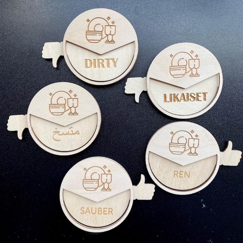 May include: Five wooden round dishwashing signs with a thumbs up or thumbs down icon. The signs have the words "Dirty", "LikaisSet", "Sauber", "Ren", and "مستح" on them.