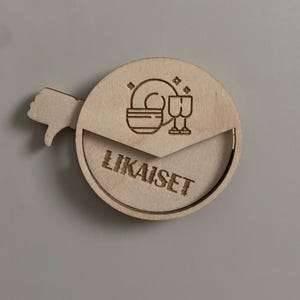 May include: A wooden round sign with a thumbs down icon and the text "LIKAISET" in a circle. The sign has a small cutout in the shape of a plate and two glasses.