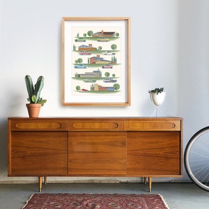 May include: A framed print of a mid-century modern illustration featuring a row of houses with cars in front of them. The houses are in various shades of orange, yellow, and brown. The cars are in shades of green, blue, red, and white. The background is a light cream color with green trees.