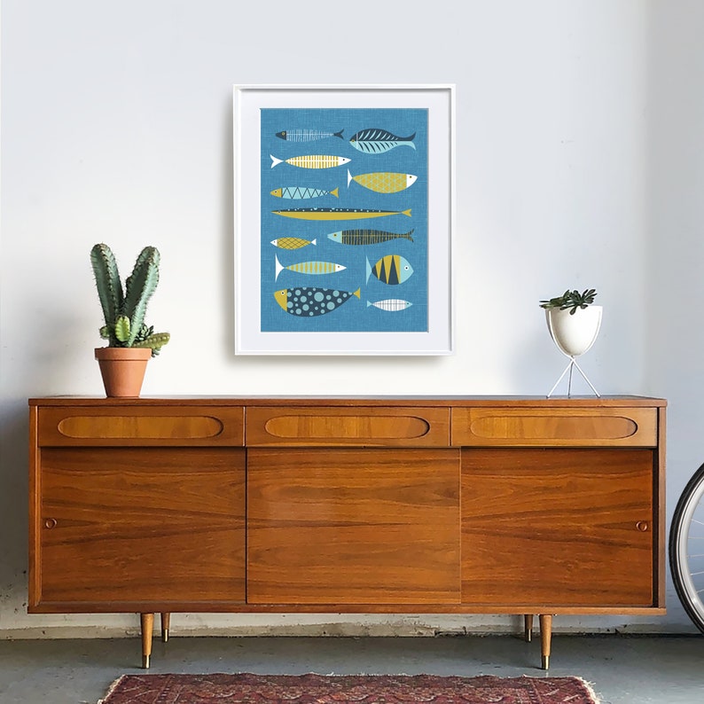 May include: A framed print of a blue background with a collection of stylized fish in various colors and patterns, including yellow, blue, and white. The fish are arranged in a vertical row.