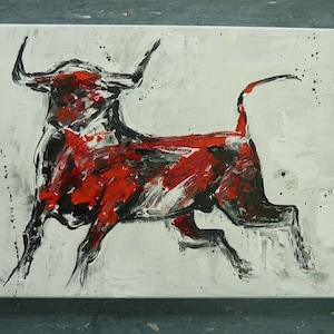 May include: Abstract painting of a bull in motion, rendered with bold brushstrokes. The artwork features a red and black bull against a white background, with paint splatters adding texture. The canvas is rectangular.