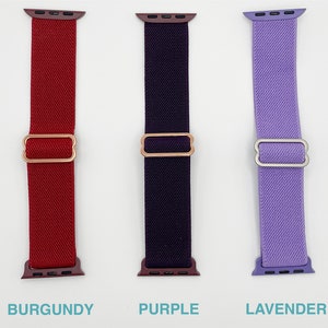 May include: Three Apple Watch bands in different colours: burgundy, purple, and lavender. Each band has a metal clasp.