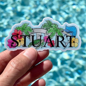 May include: A sticker with a blue, green, and white tropical design. The sticker features a sea turtle, a marlin, palm trees, and flowers. The word "STUART" is written in black letters across the sticker.